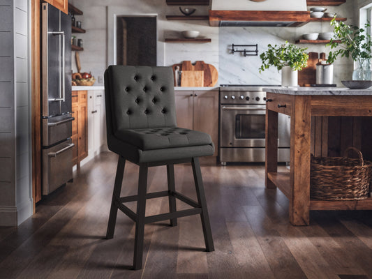 Dark grey button tufted bar stools with wooden legs and footrest, featuring plush fabric upholstery and a classic design, perfect for modern and contemporary kitchen or bar settings.