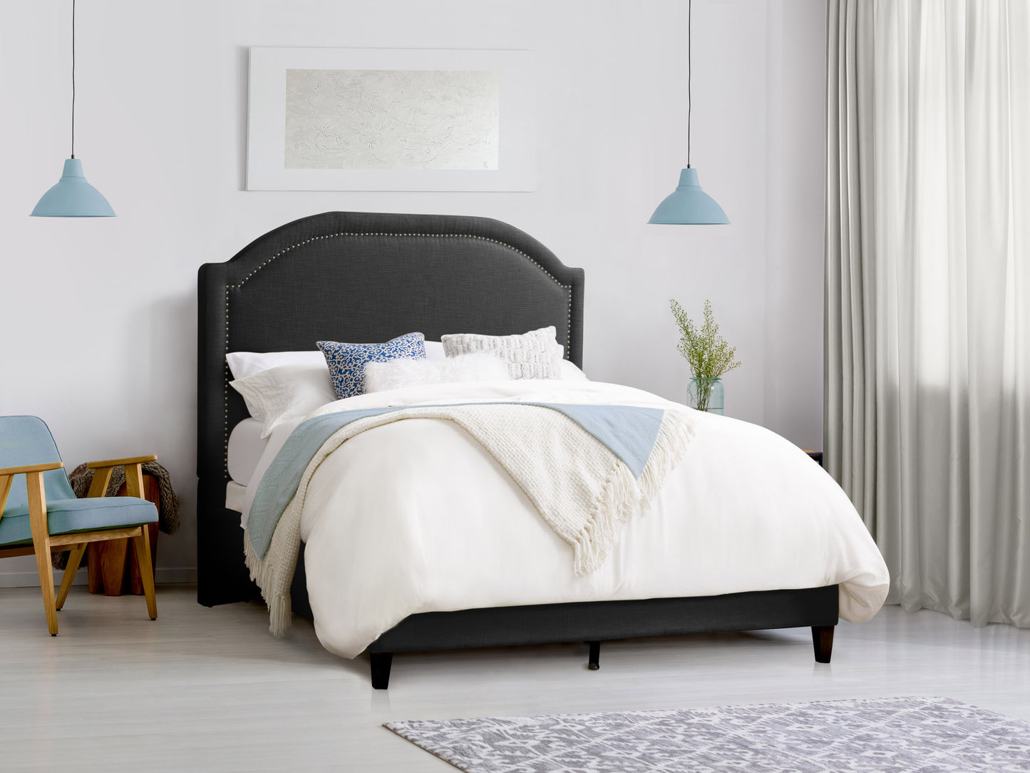 Gray upholstered double bed with tufted headboard, wooden legs, and soft fabric finish set in a modern bedroom with neutral tones and minimalist decor.