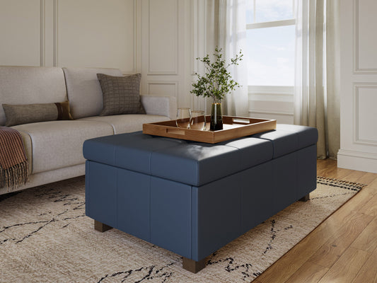 Blue upholstered ottoman with tufted top, wooden legs, and built-in storage compartment. Ideal for living room or bedroom decor, offering both seating and organizational solutions.