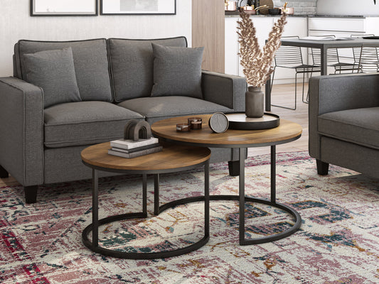 Round nesting coffee tables with brown wood tops, black metal legs, and a modern minimalist design. The larger table has a smooth surface, while the smaller table can be tucked underneath for space-saving versatility.