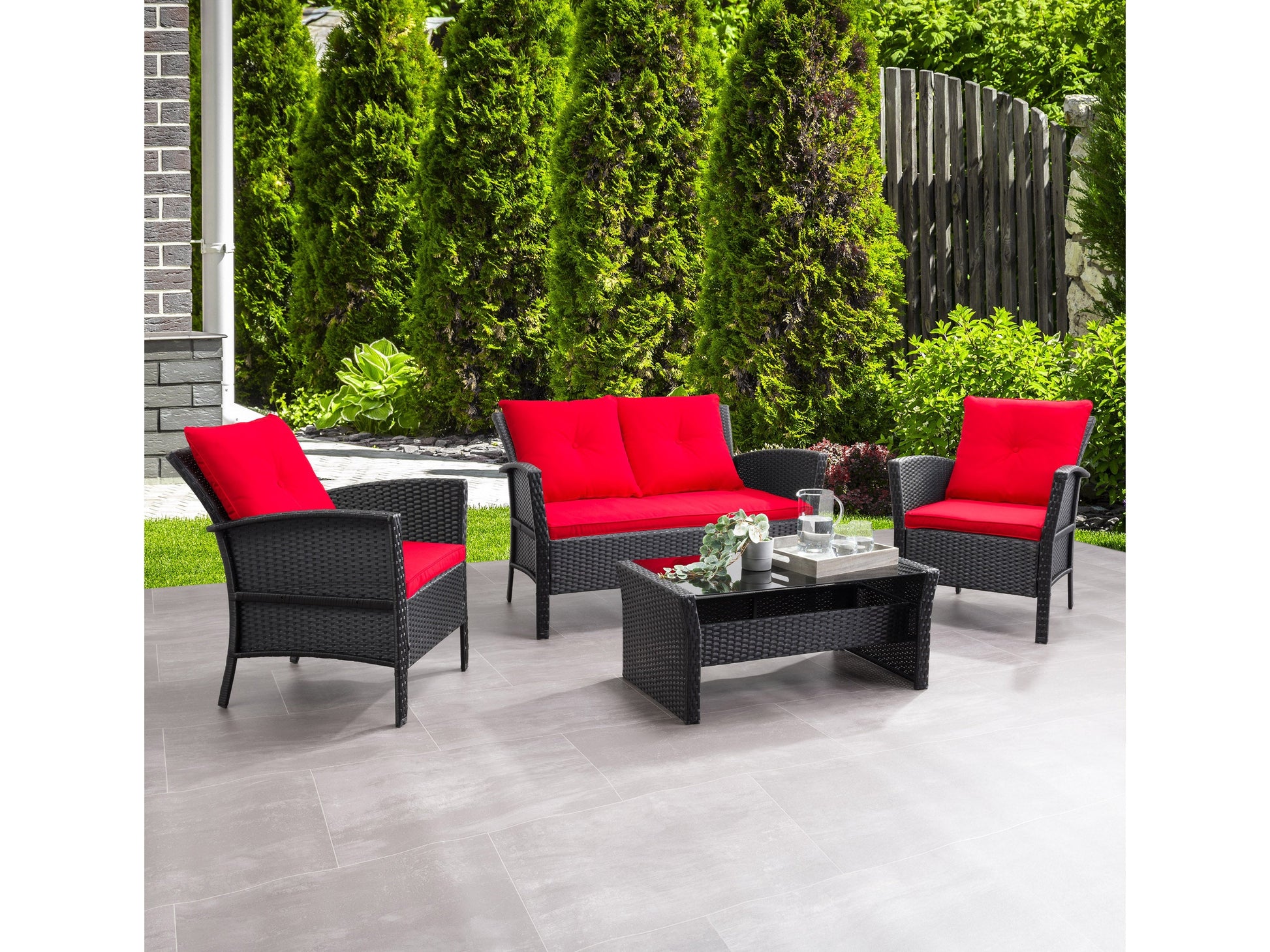 Black and red wicker patio conversation set with a modern design, featuring a loveseat, two armchairs with plush red cushions, and a glass-topped coffee table. Ideal for outdoor relaxation and entertaining.